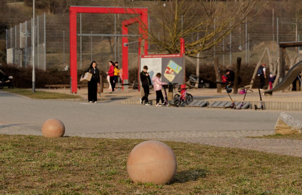 Městský park s dětským hřištěm stylově doplněný betonovými koulemi